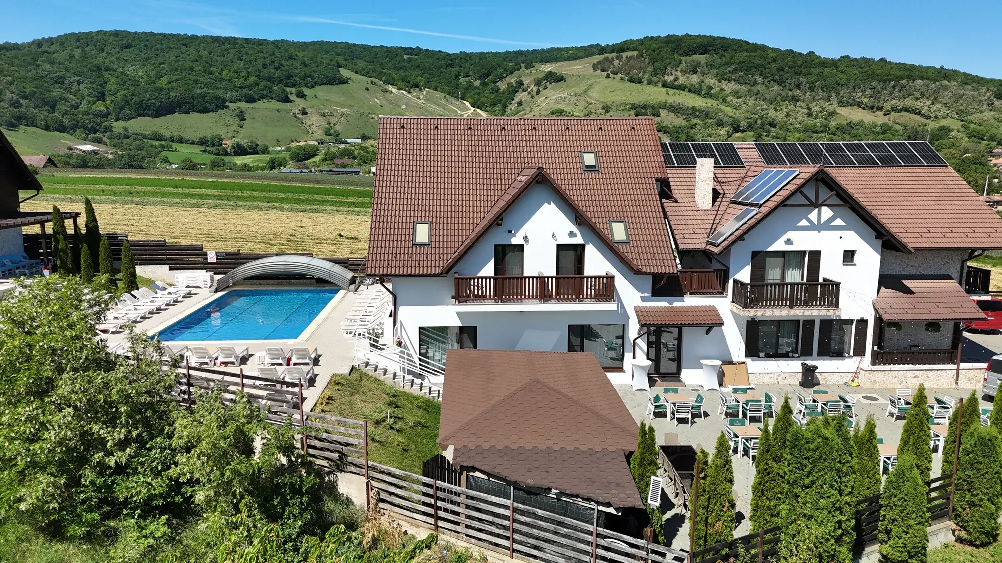 Vedere aeriană asupra pensiunii Perla Transilvaniei, cu piscina și dealurile din Moldovenești
