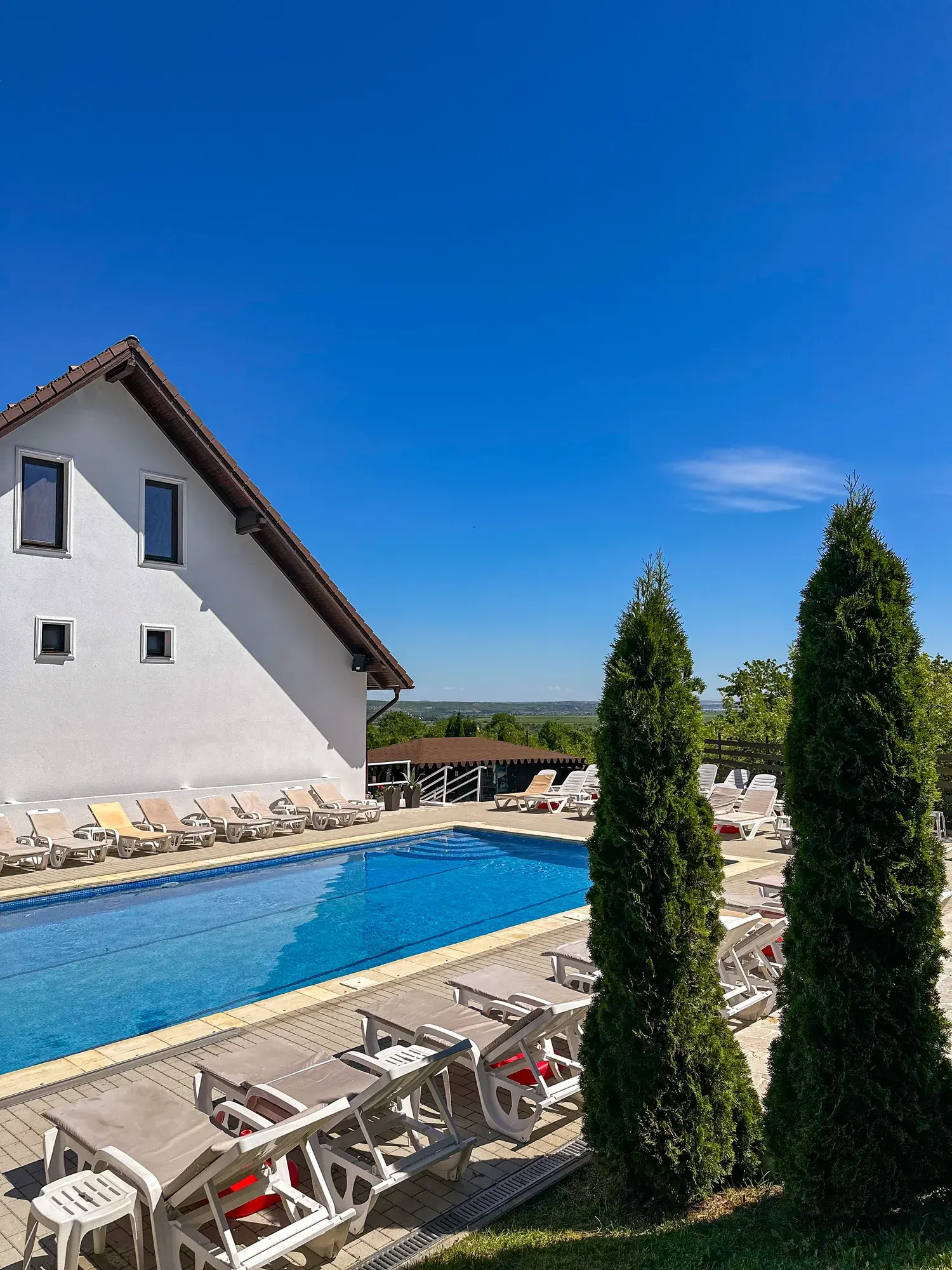 Piscina exterioară și șezlongurile din curte