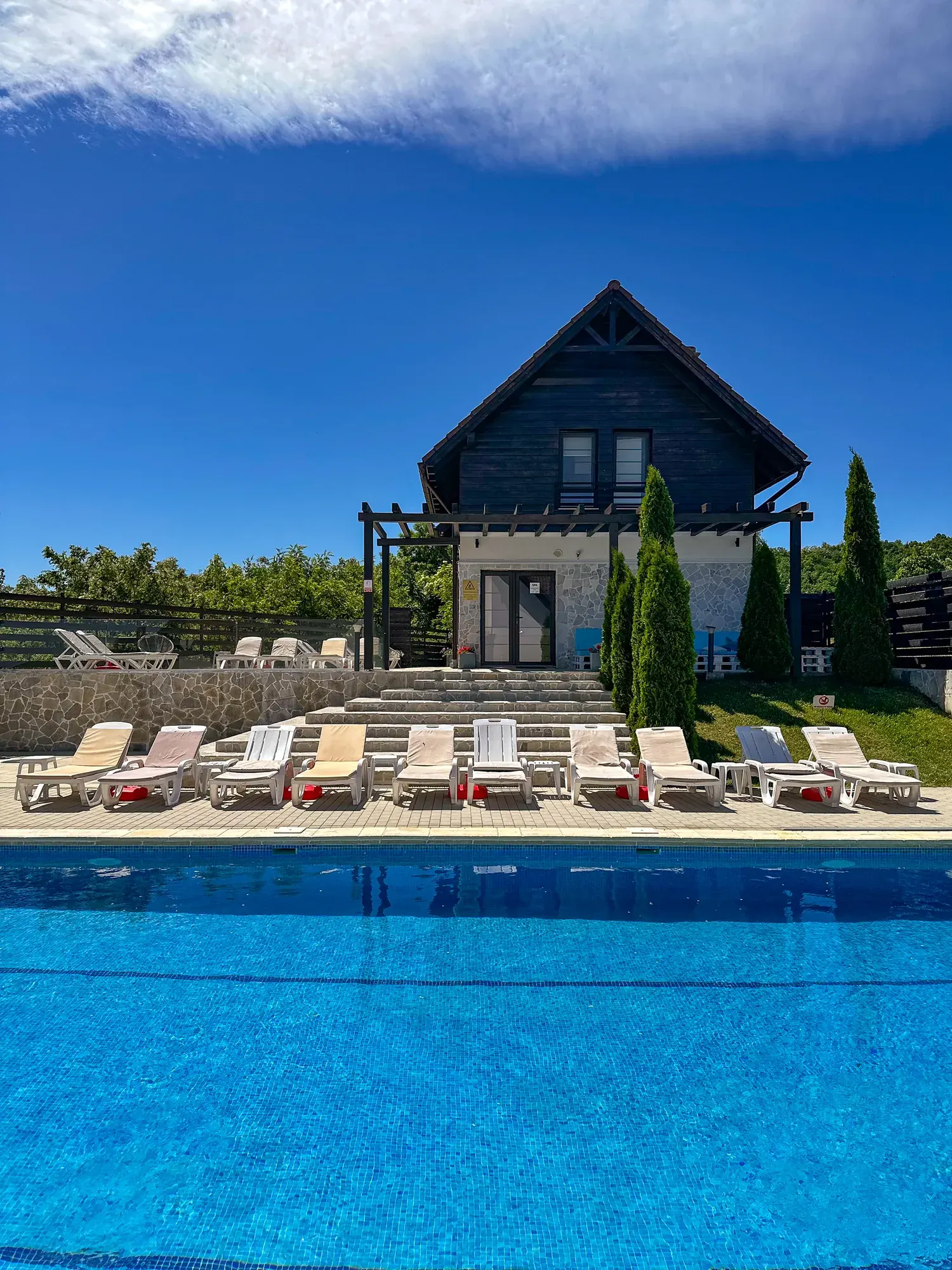 Piscina în aer liber, șezlongurile și clădirea pensiunii
